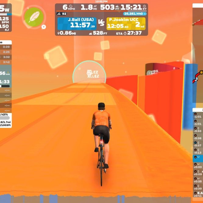 A cyclist riding on a vibrant, orange virtual road in Zwift, with various performance statistics displayed on the screen, including power output, speed, distance, and position in a race. The scene shows the cyclist in an orange jersey, pedaling along a narrow path with colorful digital structures on either side.