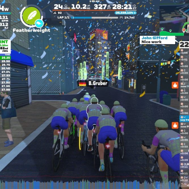 A group of virtual cyclists competing in an event called "Alley Sprint" on Zwift. The cyclists are riding closely together on a digital city street, with colorful confetti falling around them. A leaderboard shows the top rankings and times, while spectators can be seen in the background.