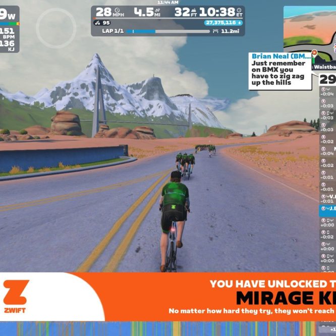 A group of cyclists are riding on a virtual road in Zwift, surrounded by mountains and a desert landscape. The scene includes cycling statistics displayed at the top, such as power output and speed, along with a message about unlocking a kit. A leaderboard on the right shows the names and stats of participants. There are rocky formations and greenery in the background, creating a vibrant virtual environment.
