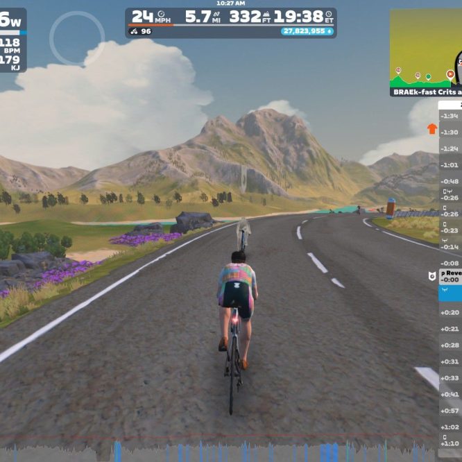 A virtual cycling scene in Zwift, showing a cyclist riding on a paved road surrounded by mountains and greenery. The cyclist is wearing a colorful jersey, and various stats like power output, speed, and heart rate are displayed on the screen. A leaderboard on the side shows other participants' performance metrics.