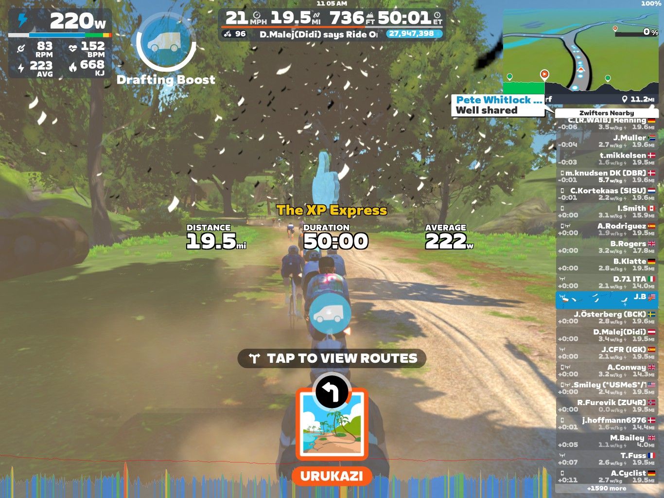 A screenshot from Zwift showing a virtual cycling scene with a group of cyclists on a wooded path. Key statistics display the cyclist's power output, distance of 19.5 miles, duration of 50 minutes, and average speed of 21 mph. There is a drafting boost indicator and a menu option to view routes. The interface includes details about nearby riders and their stats.