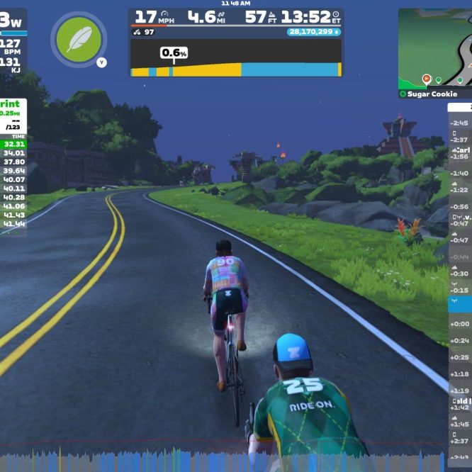 A digital cycling scene in Zwift showing two cyclists on a road with a curved path. The screen displays various stats such as power output, speed, distance, and heart rate, along with a list of riders' rankings and times. The background includes virtual landscapes with trees and buildings under a night sky.