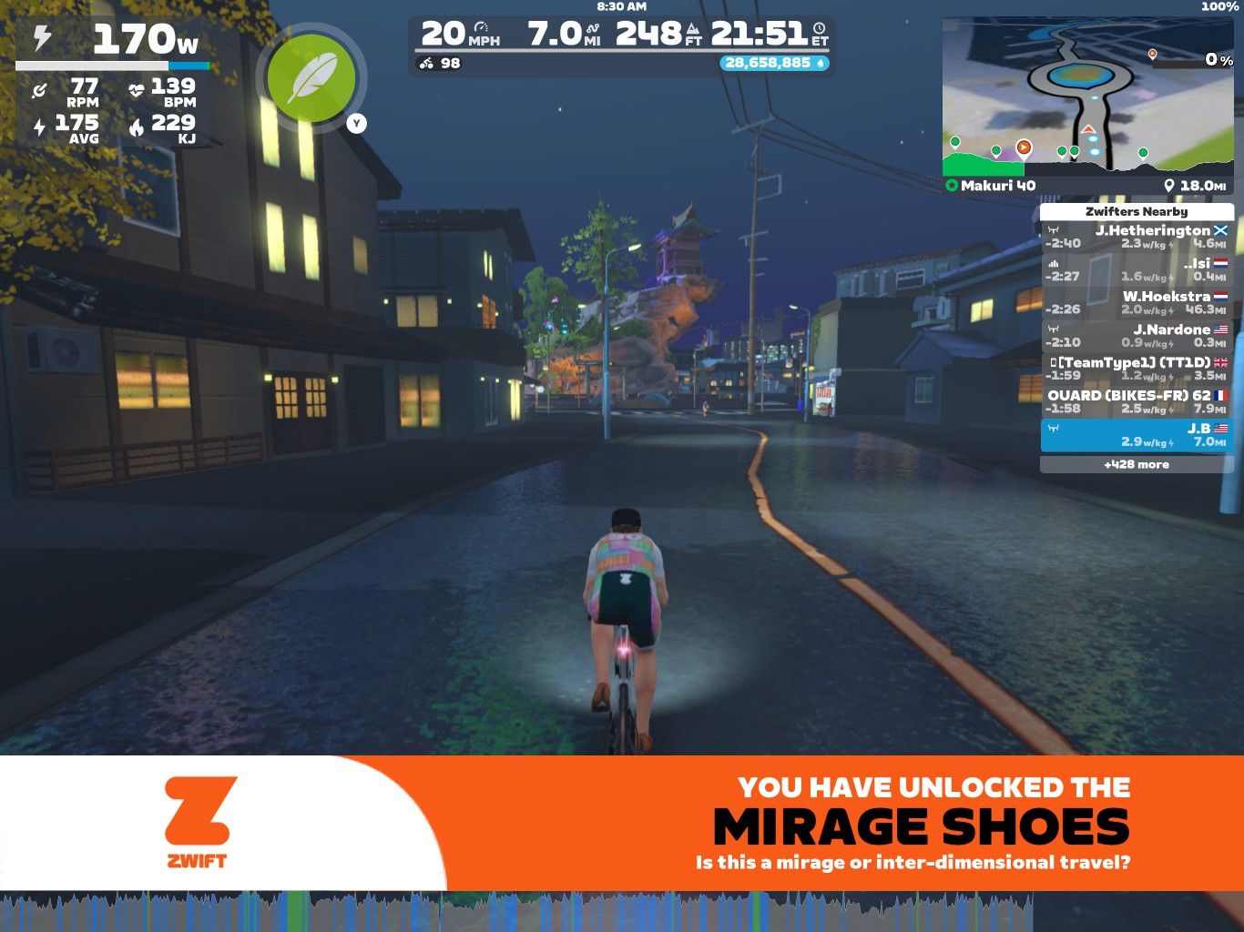 A cyclist in a virtual environment rides on a road at night, with illuminated buildings lining the street. The cyclist's stats display on the left, showing power, speed, and heart rate. A message at the bottom indicates the unlocking of