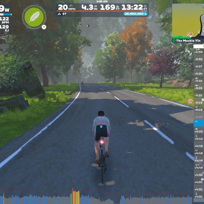 A cyclist rides on a digital road in Zwift, surrounded by trees and greenery. The screen displays cycling statistics, including power output, speed, and heart rate. A map in the corner shows the route and a list of nearby cyclists.