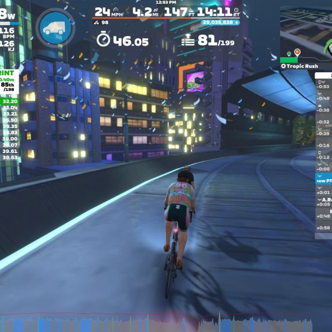 A cyclist is riding on a digital course in Zwift, surrounded by a colorful urban setting with buildings illuminated at night. The screen displays various statistics, including power output, speed, distance, and current rankings in a sprint event. In the background, there are graphics indicating nearby riders and their performance metrics.