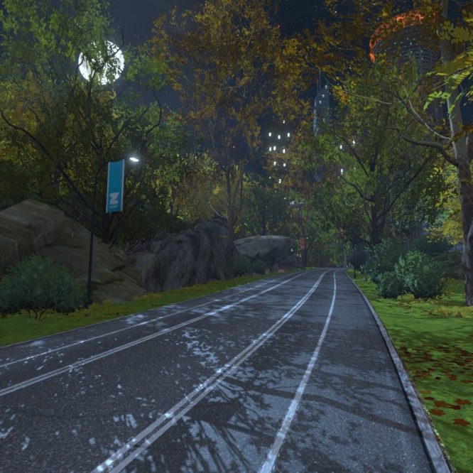 A winding path in a lush, green park is illuminated by soft lighting at night, flanked by trees with autumn foliage. A few large rocks are visible alongside the path, and a flag with the Zwift logo can be seen on a nearby pole.