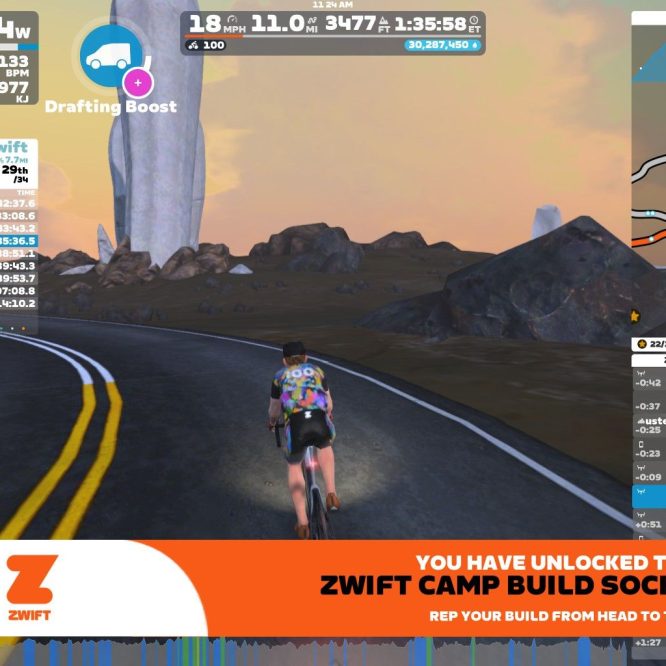 A cyclist in a virtual environment, riding on a winding road with a scenic background, representing the Zwift platform. The image displays performance stats, including power output and heart rate, as well as a leaderboard with participant names and times. A promotional banner for Zwift Camp Build Socks is shown at the bottom.