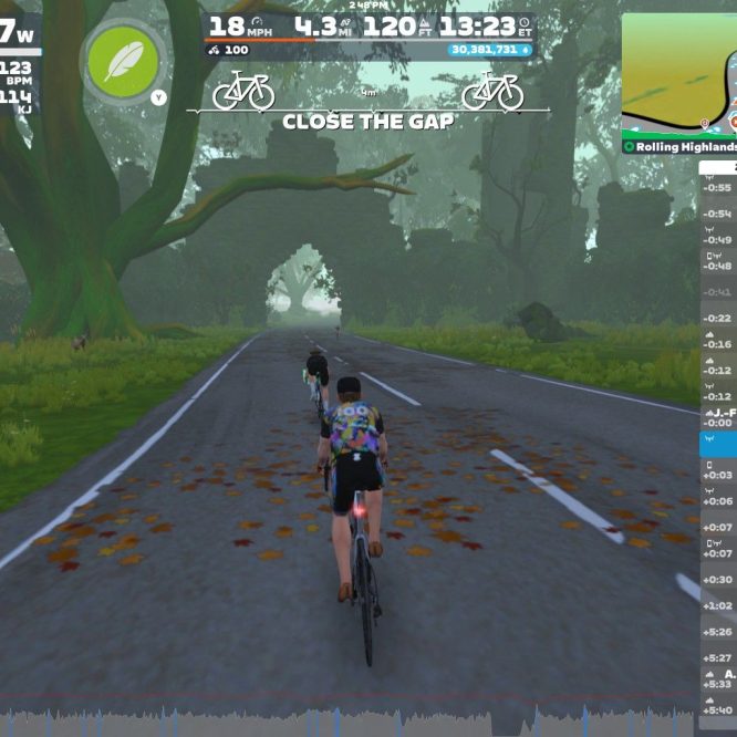 A digital cycling scene from Zwift shows three virtual cyclists riding on a leaf-strewn road surrounded by large trees. The interface displays various cycling statistics, including power output and pace, along with a map and a list of nearby users. The environment is lush and green, with a misty ambiance.