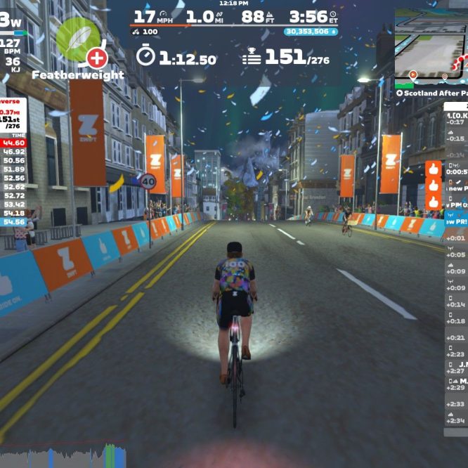 A cyclist rides down a digital street in the Zwift virtual cycling platform. The scene shows a city environment with buildings and colorful banners. On-screen statistics include power output, speed, cadence, heart rate, and rankings for participants in a cycling event. Snowflakes are falling in the virtual scene, and additional metrics about nearby cyclists are displayed.