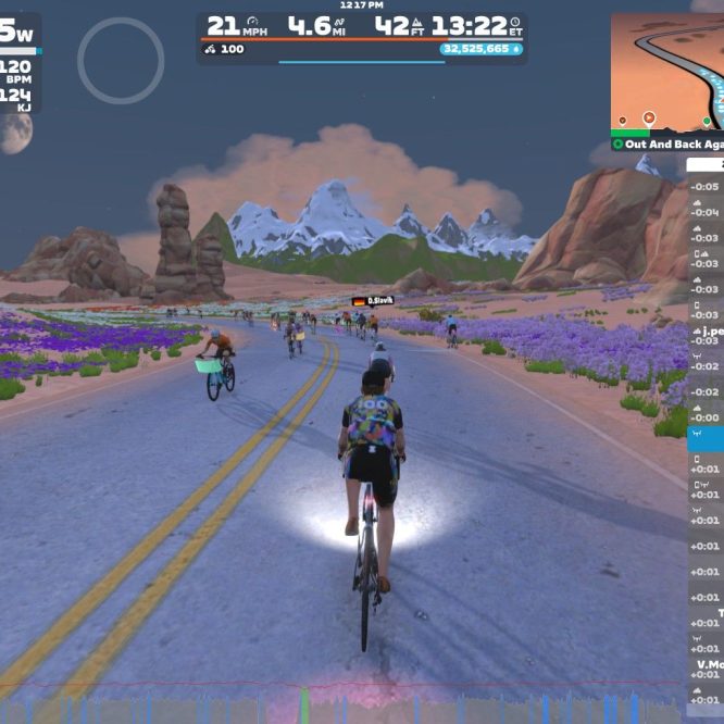 A screenshot from Zwift shows several cyclists riding on a road surrounded by colorful flowers and rocky mountains. The display includes cycling statistics such as wattage, speed, and distance, along with a list of nearby riders. The setting features a clear sky with a visible moon.