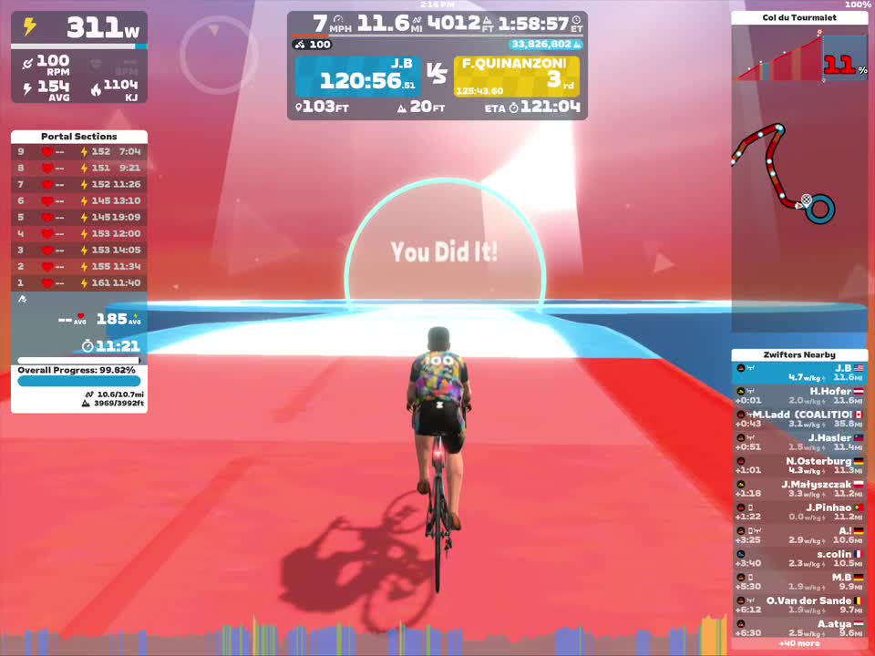 A cyclist is riding in a virtual environment on Zwift, approaching a glowing finish line with the message 
