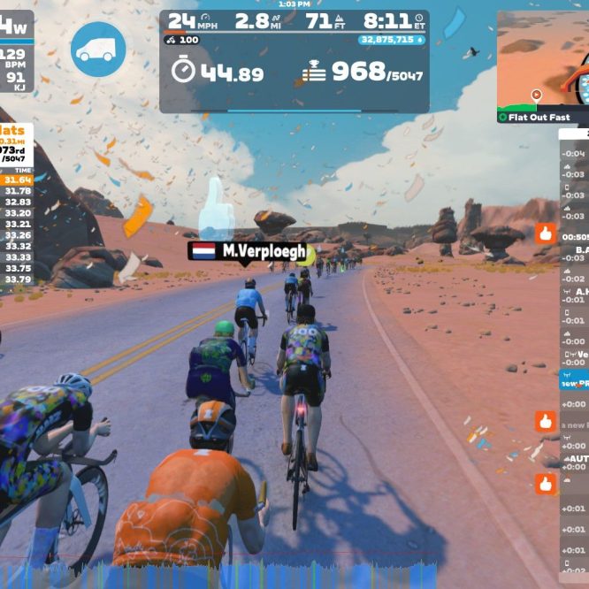 A dynamic virtual cycling scene from Zwift, featuring a group of riders on a road in a desert-like environment with colorful landscape elements. The interface displays various statistics, including power output, speed, distance, and leaderboard results for participating cyclists. The atmosphere suggests an energetic and competitive race atmosphere.