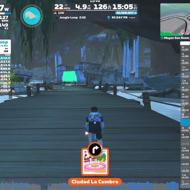 A screenshot from Zwift showing a virtual cycling environment on the Jungle Loop. The cyclist is traveling on a wooden bridge surrounded by green trees and rock formations. The screen displays various statistics, including speed, power output, and heart rate. Rankings and results for multiple cyclists are shown on the left side, while nearby Zwifters and a map are visible on the right. The location is labeled "Ciudad La Cumbre."