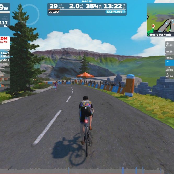 A cyclist rides along a virtual road in Zwift, surrounded by greenery and mountains in the background. The screen displays performance metrics, including speed and power, as well as information about nearby cyclists.