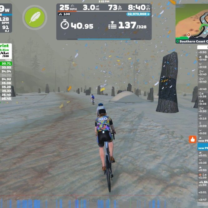 A cyclist rides on a snowy path in Zwift, surrounded by tall stone markers. The screen displays performance metrics, including watts, speed, and heart rate, alongside a leaderboard showing live results of a sprint event.