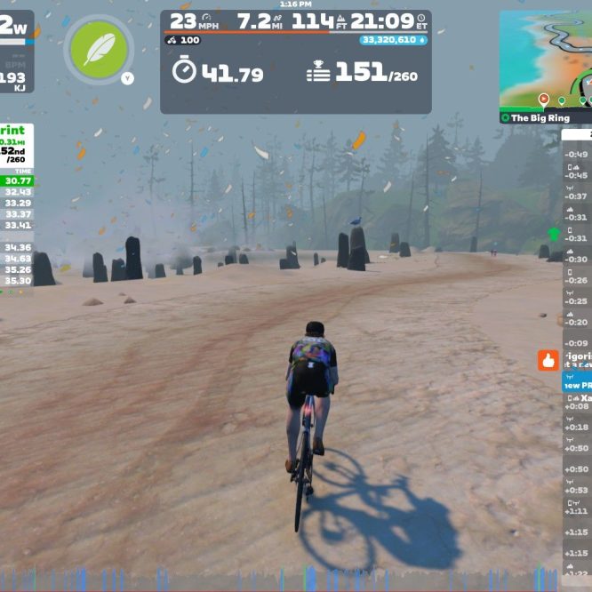 A cyclist is riding on a virtual course in Zwift, displaying stats such as speed (23 mph), distance (7.2 miles), and power output (182 W). The scene features a misty landscape with standing stones, and a leaderboard shows current race results. Various metrics, including elevation and rider positions, are visible on the screen.