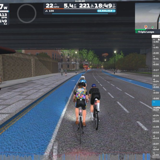 A digital cycling scene in Zwift, featuring cyclists riding on a blue bike lane under an overpass. The setting includes a path with bikes parked nearby, city buildings in the background, and a visible leaderboard displaying nearby riders' stats and times. The time on the clock shows 18:49.